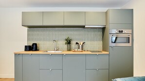 Una cocina compacta con armarios grises, encimera de madera, horno empotrado y un lavabo.