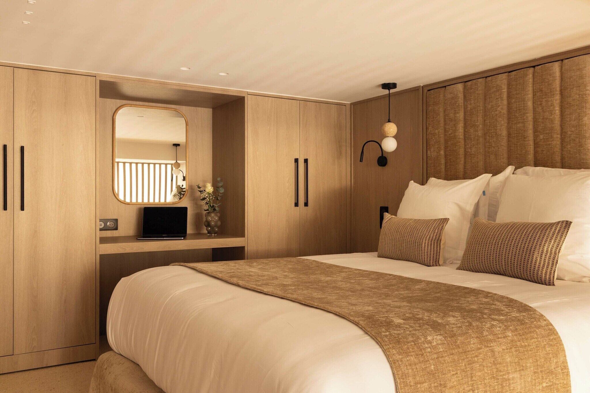 Une chambre moderne avec un grand lit, une armoire intégrée, un miroir et une table de chevet avec une lampe.