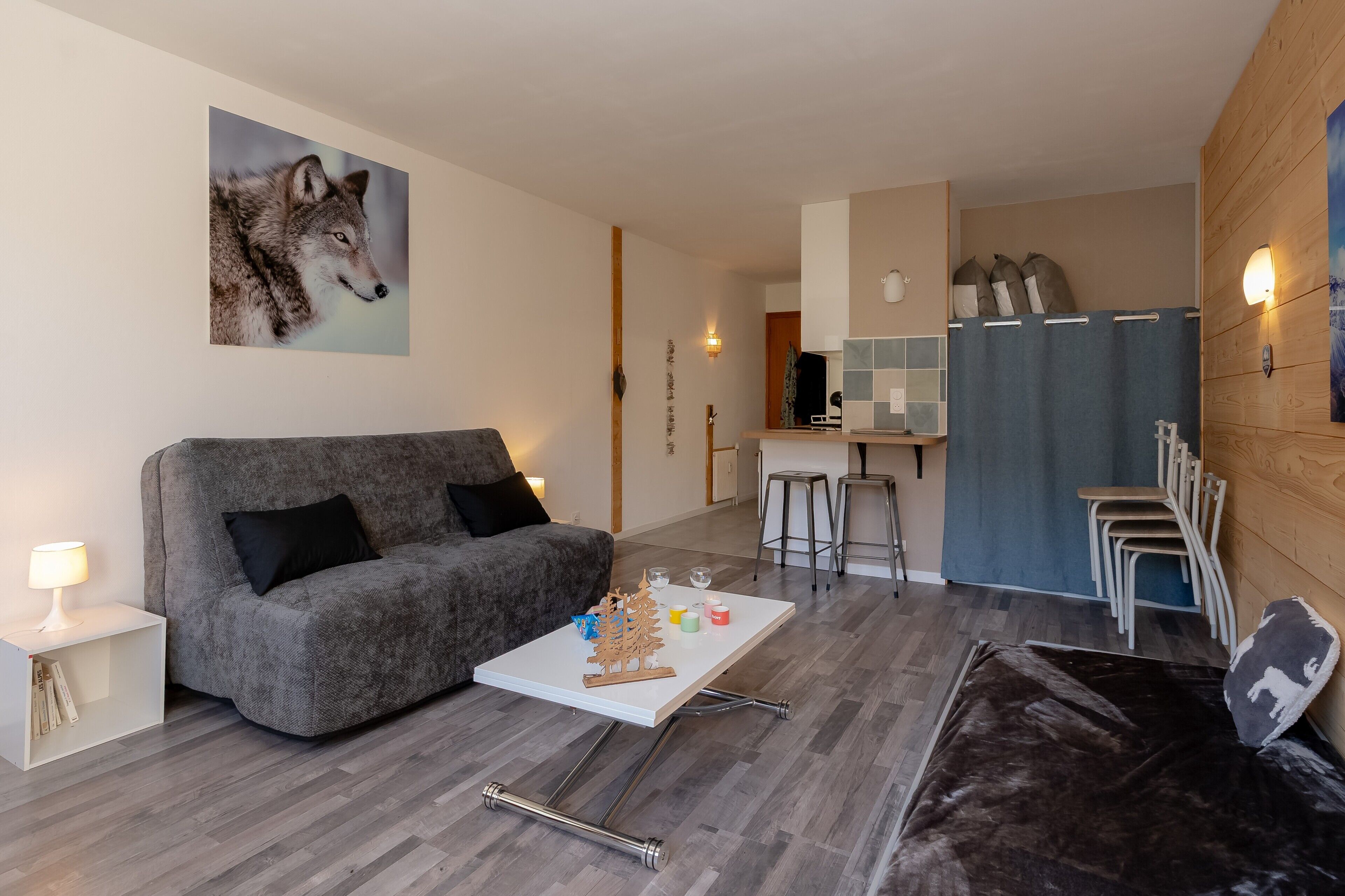 A modern living room with a grey sofa, a white coffee table, and a painting of a wolf.
