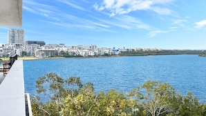 Une vue sur le front de mer, avec des bâtiments modernes, un ciel dégagé et une étendue d’eau calme.