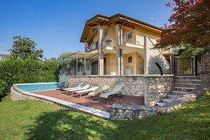 Una casa a due piani con facciata in pietra, un balcone e una piscina.