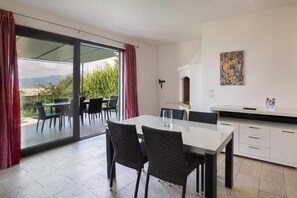 Una cucina moderna con angolo pranzo, ampie porte scorrevoli in vetro e vista sul verde.