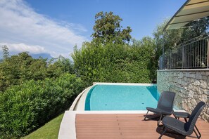 Una piscina con un pontile in legno e due sdraio.