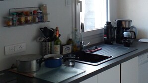 Una cucina con pensili bianchi, un piano di lavoro nero, una finestra e una macchina per il caffè.
