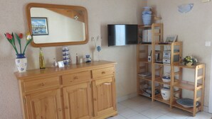 Un mobile in legno con cassetti, uno specchio e una televisione appesa al muro.
