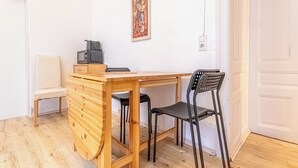 Un piccolo tavolo di legno con due sedie nere, una sedia bianca e un televisore su un mobile in legno.