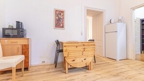 Una piccola cucina accogliente con microonde, macchina del caffè e frigorifero. C'è un tavolo di legno e una sedia, e un quadro appeso al muro.