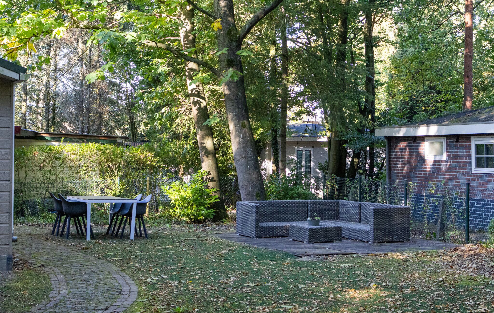 A patio with outdoor furniture, a brick wall, and a garden area with trees.