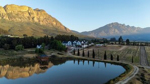 A lakeside property with white buildings, a dock, and a mountain backdrop.