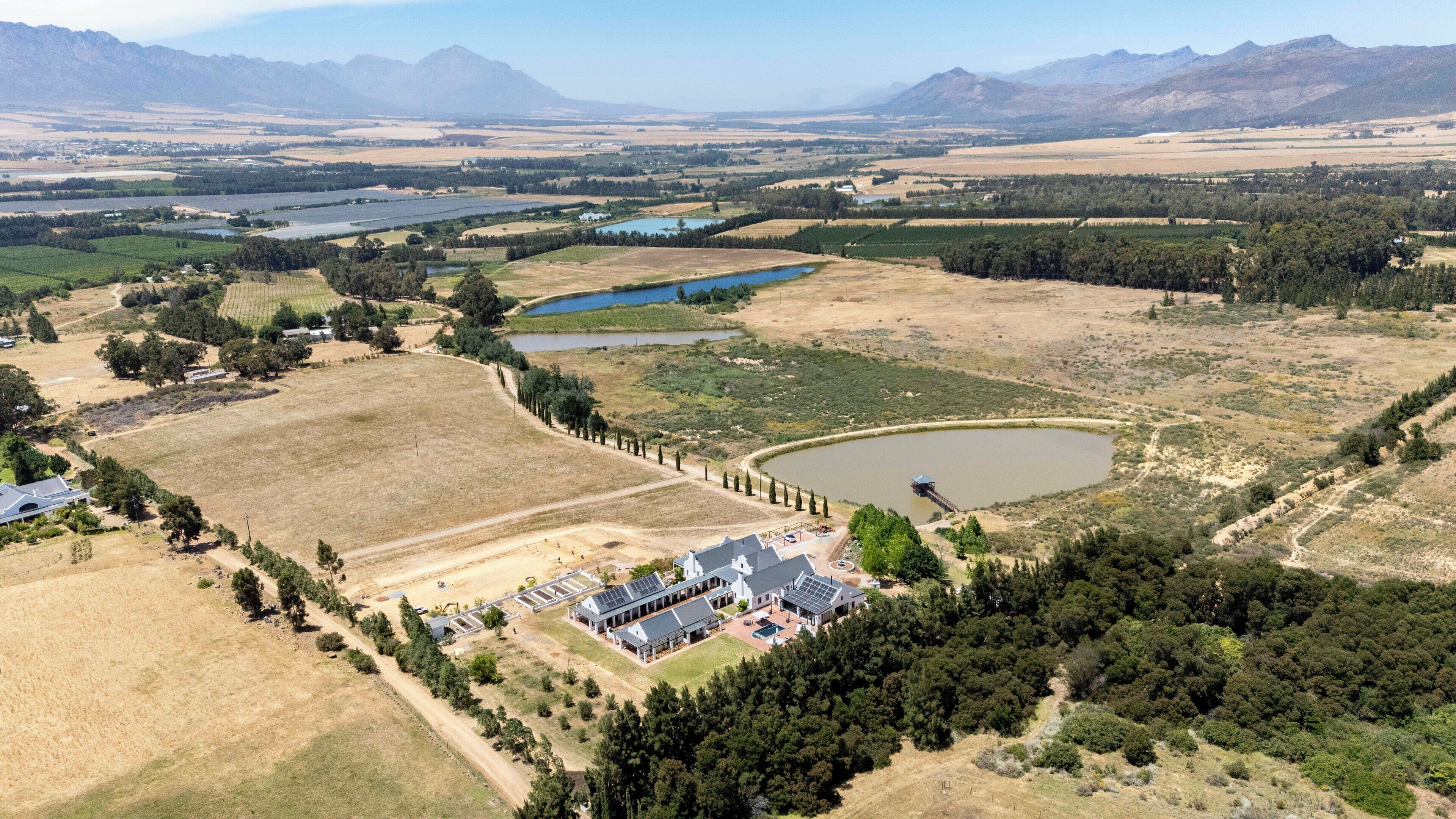 A large estate with multiple buildings, a pond, and surrounding fields.