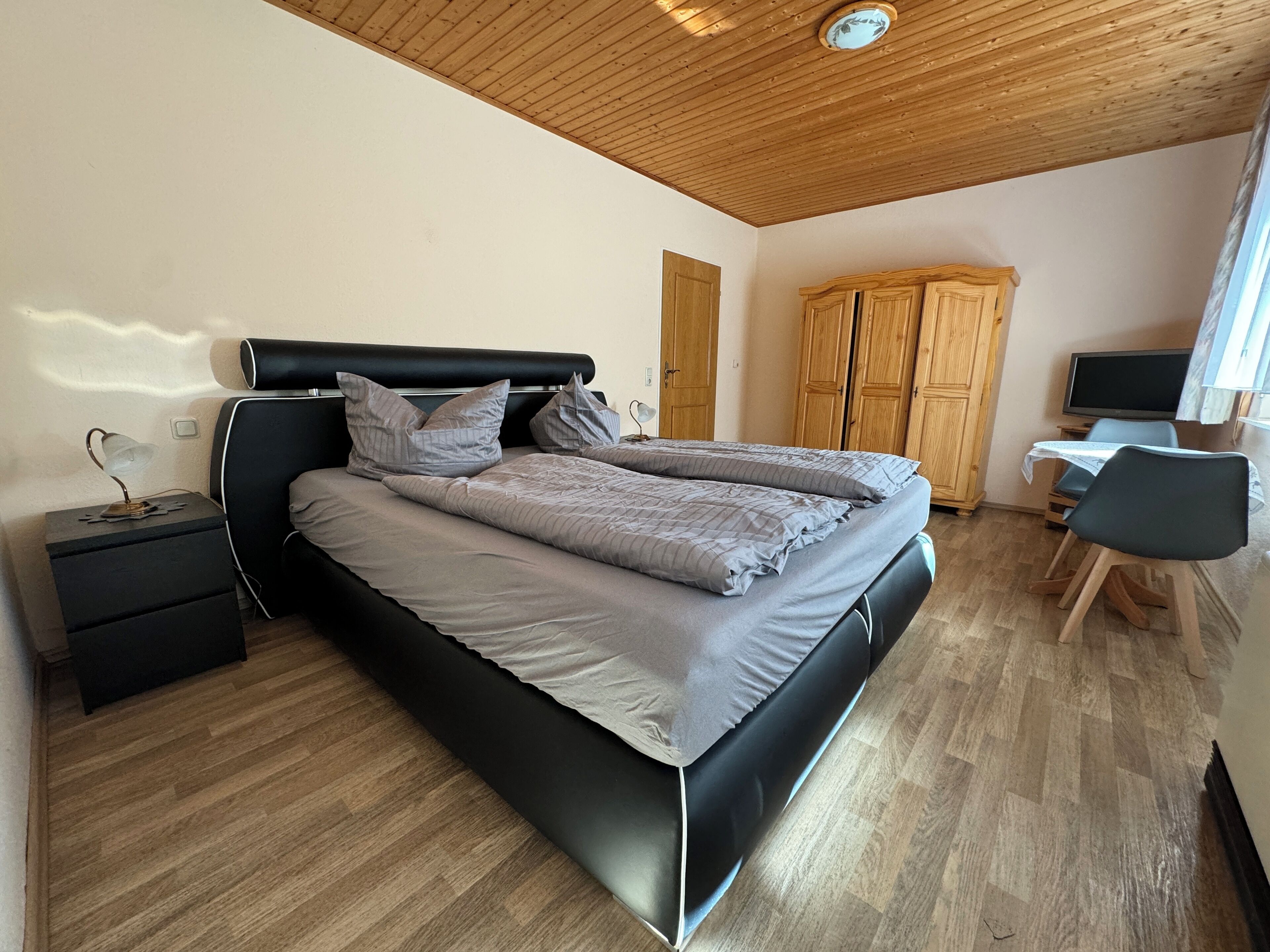 Une chambre à coucher comprenant un lit, une table de chevet, une lampe, une armoire, un bureau, une chaise et un téléviseur.