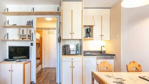 Una cocina funcional con armarios de madera, una mesa de comedor y un televisor.