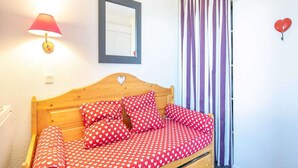 A bedroom with a wooden bed, red heart-patterned bedding, a wall-mounted mirror, a striped curtain, and a red heart decoration. - Peaceful Alpine Escape, Risoul (Risoul)