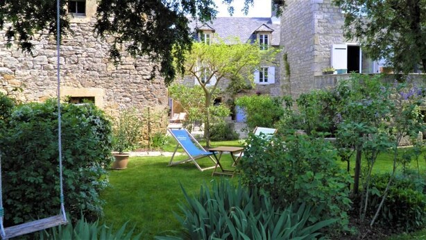 A stone building with a grassy yard, a swing, and a blue lounge chair. - Le Clos du Barry (Laissac-Severac-l'Eglise)