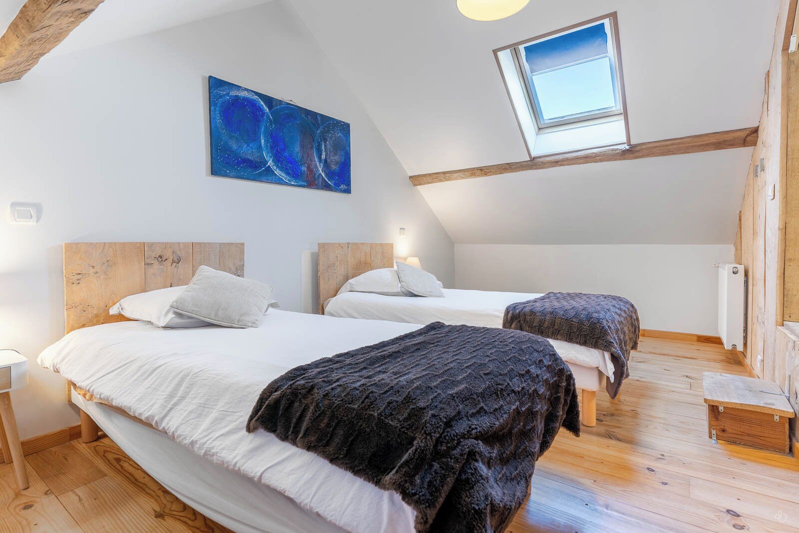 Un dormitorio con dos camas, un tragaluz y un cuadro en la pared.