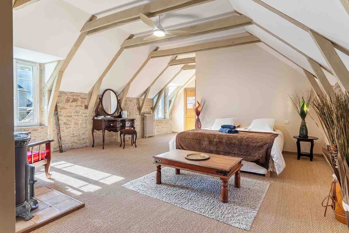Une chambre mansardée accueillante, avec un lit, une commode, un miroir et une petite table.