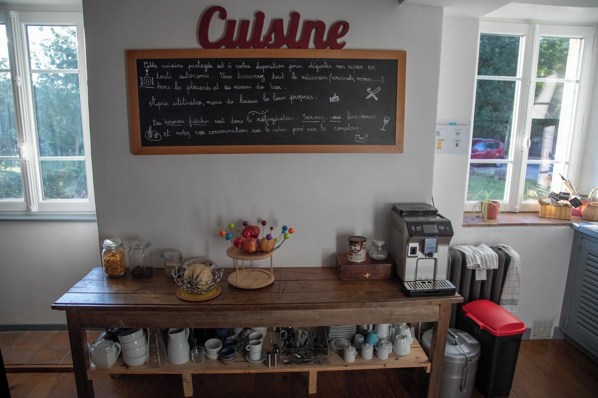 A kitchen area with a chalkboard menu, a coffee machine, and various kitchen utensils and containers.