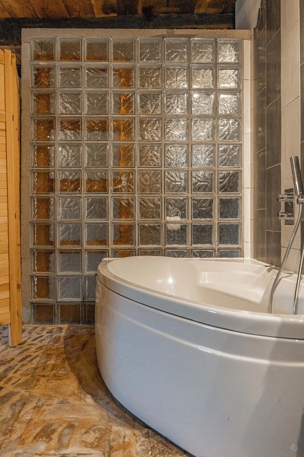 Un baño con bañera, pared de azulejos y suelo de madera.