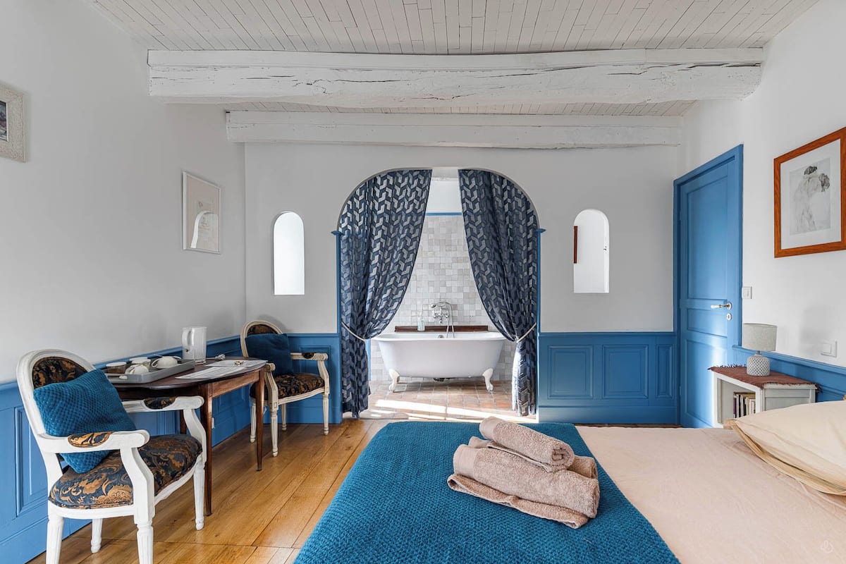 Une pièce avec une baignoire, une chaise, une table et un lit.