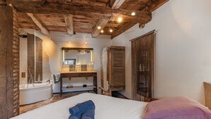 A bedroom with a wooden ceiling, a large bed, a wooden dresser, a mirror, and a window. - Le Clos du Barry (Laissac-Severac-l'Eglise)