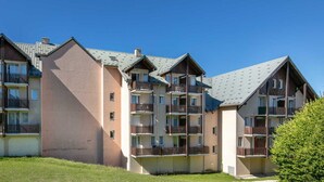 En flervåningsbostadsbyggnad med balkonger och ett sluttande tak.