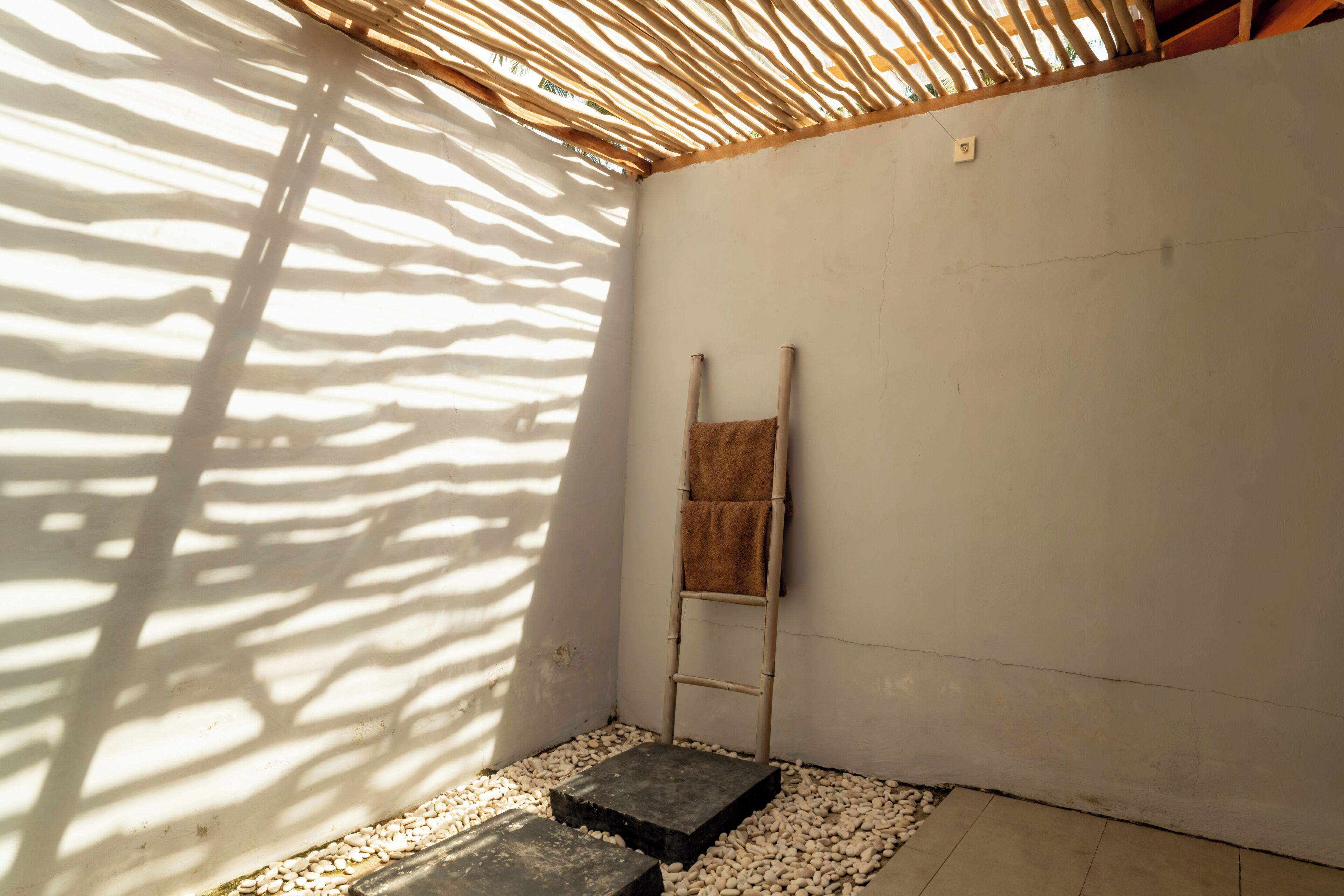 A room with a bamboo ceiling, a towel hanging on a rack, and a stone bench.