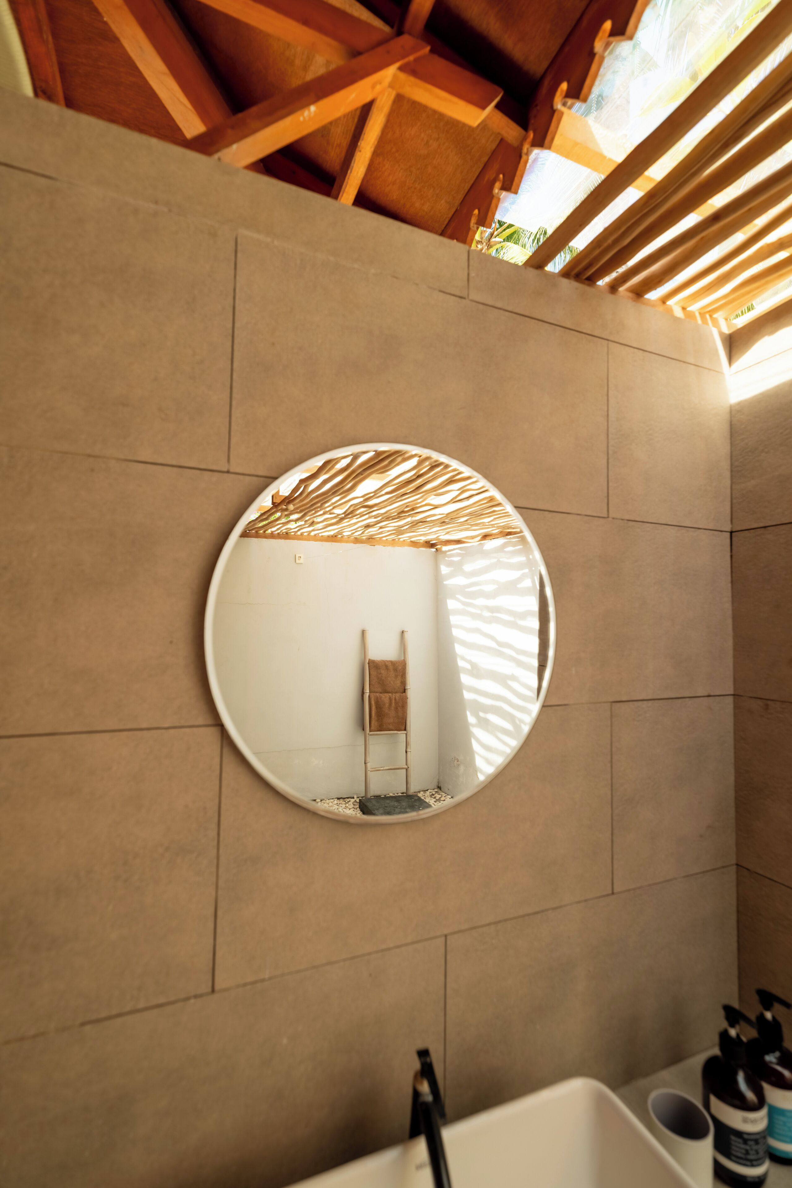 A bathroom with a round mirror, a bathtub, and a towel rack.