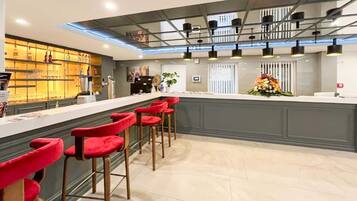 Uma área de bar moderna com balcão, banquetas vermelhas e um arranjo floral decorativo.