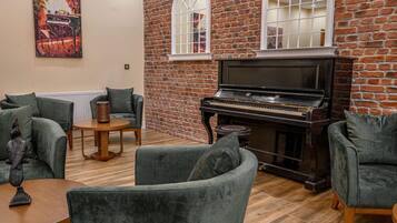 A cozy living room with a grand piano, brick walls, and comfortable seating.