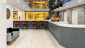 Un espace bar moderne avec un comptoir incurvé, des tabourets de bar rouges et une composition florale décorative.