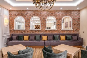 A room with a brick wall, a sofa, and a chandelier.