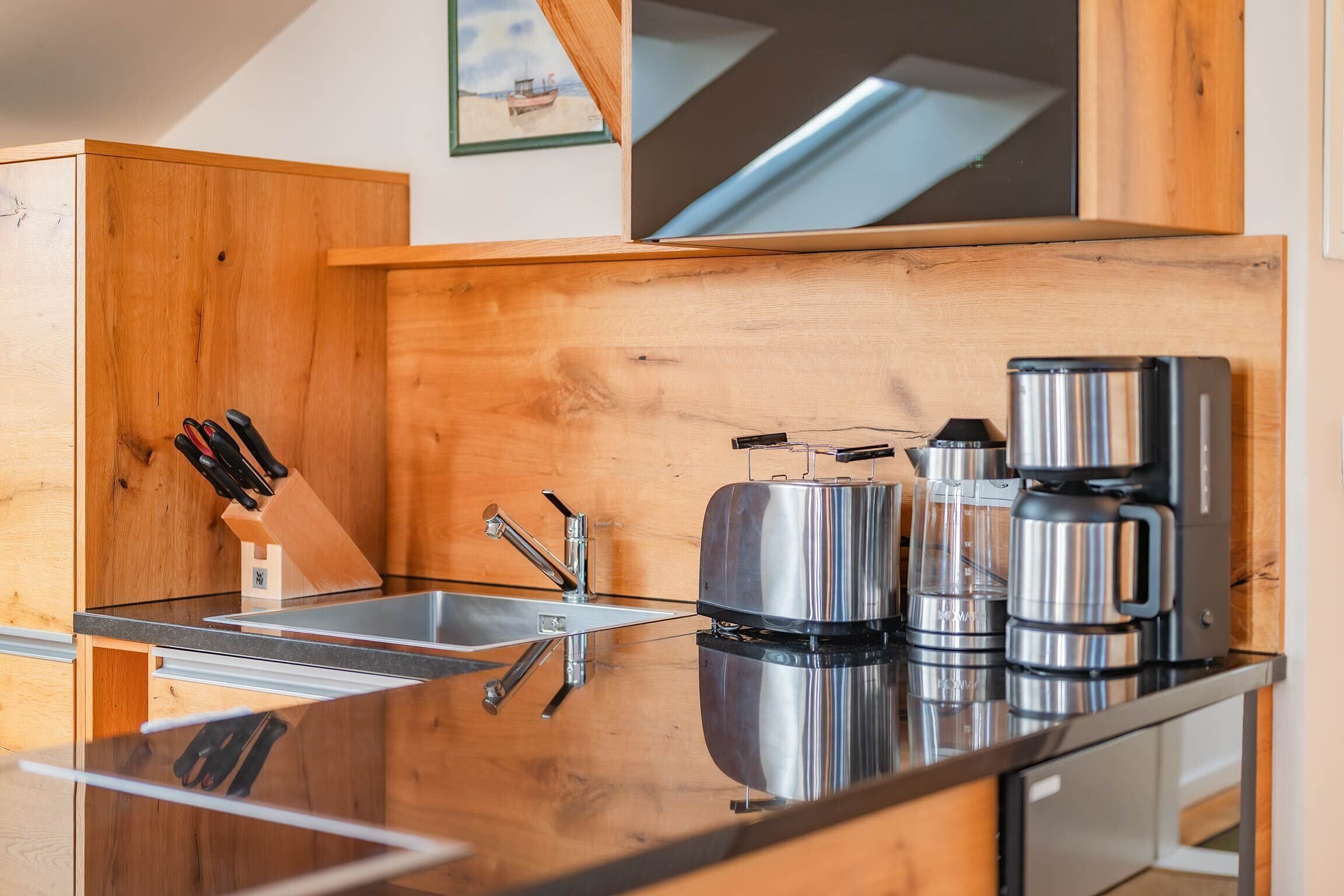 Una cocina moderna con armarios de madera, electrodomésticos de acero inoxidable y encimera de vidrio.