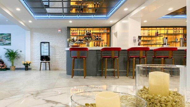 A bar area with a counter, red bar stools, and a variety of bottles.