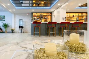 Un espace bar avec un comptoir, des tabourets rouges et une variété de bouteilles.