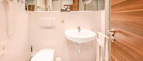 A bathroom with a white toilet, a sink, and a mirror.
