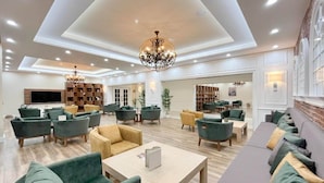 A spacious lobby with multiple seating areas, a large chandelier, and a television.