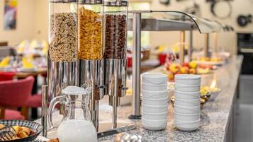 A buffet setup with various food items and a coffee dispenser.