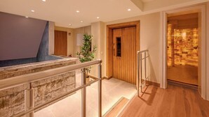A hotel lobby with a stone staircase, a wooden door, and a plant.