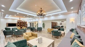 A spacious lobby with multiple seating areas, a large chandelier, and a television.