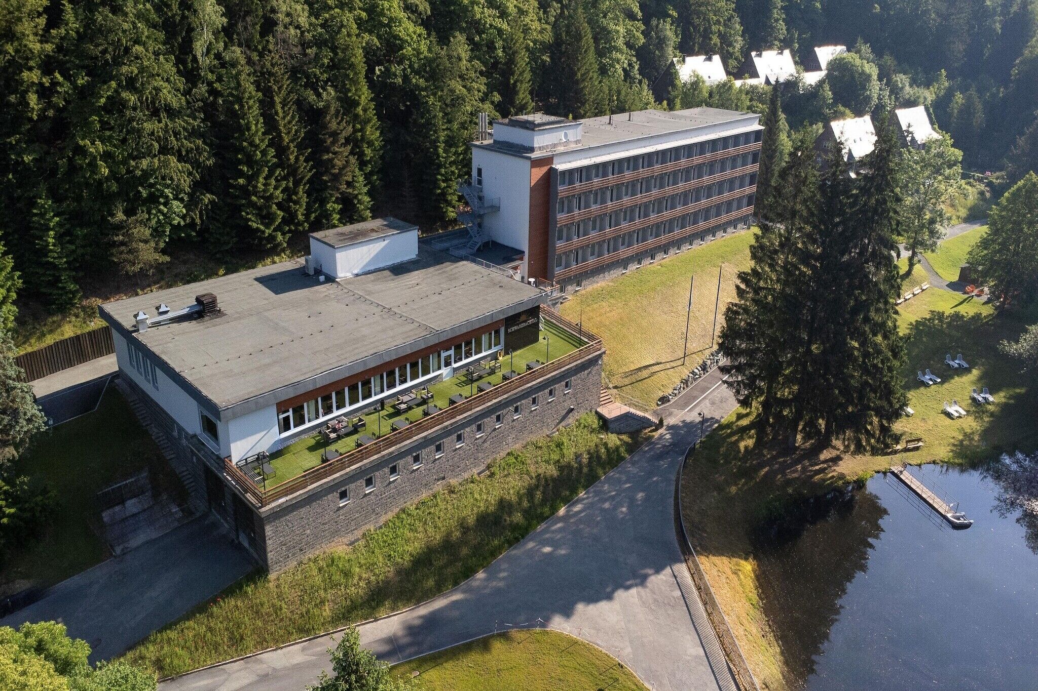 Ein Luftbild eines Gebäudekomplexes mit einem großen zentralen Bauwerk, kleineren angrenzenden Gebäuden und einem Gewässer.