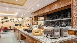 A buffet area with a variety of food items, a coffee station, and a seating area with tables and chairs.