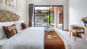 A hotel room with a bed, a desk, and a view of an outdoor pool area. - Cendana Villa Sanur (Denpasar)