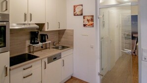 Ett modernt kök med vita skåp, en inbyggd ugn och en kaffebryggare.