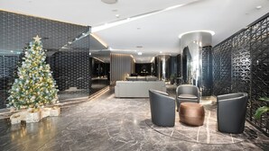 Eine moderne Lobby mit einem Weihnachtsbaum, einem weißen Sofa und grauen Sesseln.