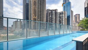 Ein Pool auf dem Dach mit Glasgeländer, umgeben von Hochhäusern.