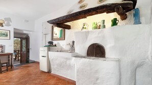 A kitchen with a white interior, a rustic wooden beam, and a white refrigerator. - Gaiano APT (Sorrento)
