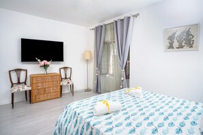A hotel room with a bed, a TV, a dresser, two chairs, a lamp, and a painting on the wall. - Gaiano APT (Sorrento)