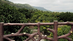 A view of a lush, green landscape with a wooden fence in the foreground. - Ambika Hills Resort (Junnar)