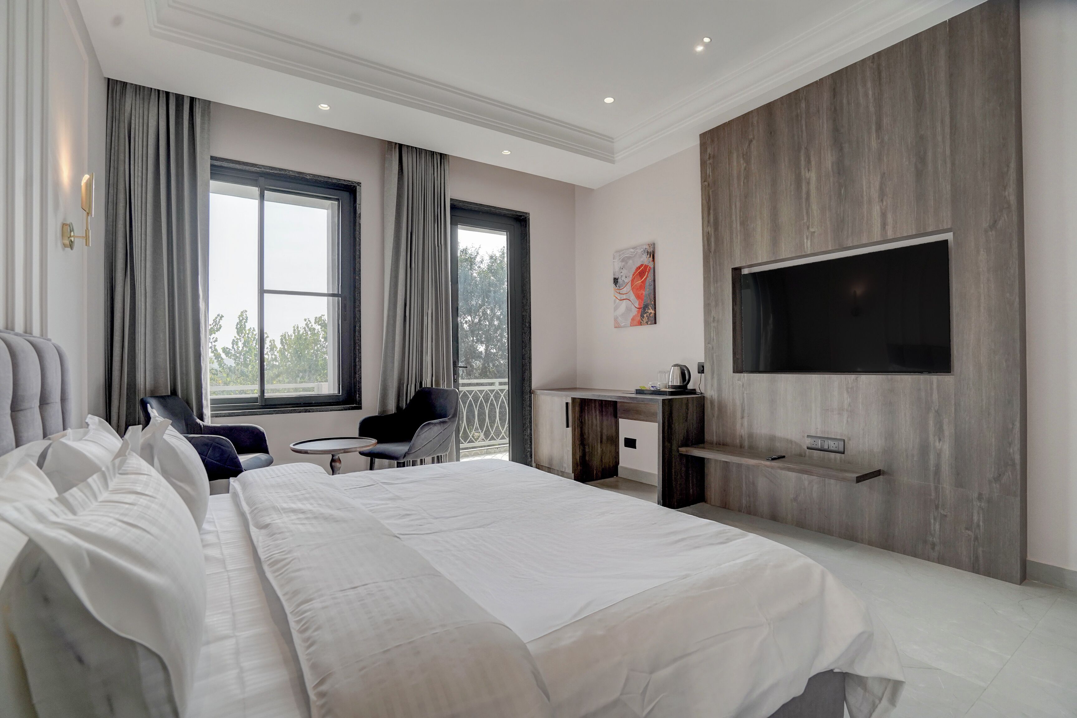 Una habitación de hotel moderna con una cama grande, un escritorio, una silla y un televisor montado en la pared.