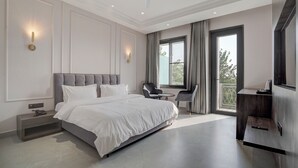 A modern bedroom with a large bed, a ceiling fan, and a view of the outdoors through a window. - Nirvana Hotel & Banquet (Batala)